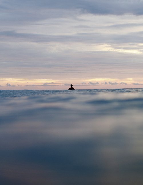 Solo Surfer Sitting Ocean Water Dusk Cloudy Sky