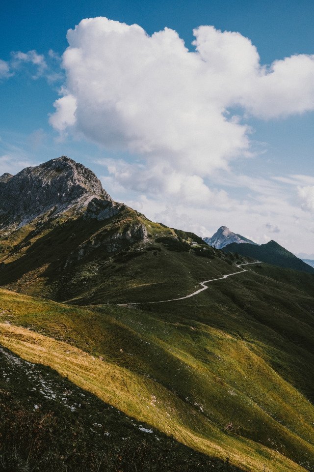 Winding Mountain Trail Green Slopes Rocky Peaks Blue Sky White Clouds