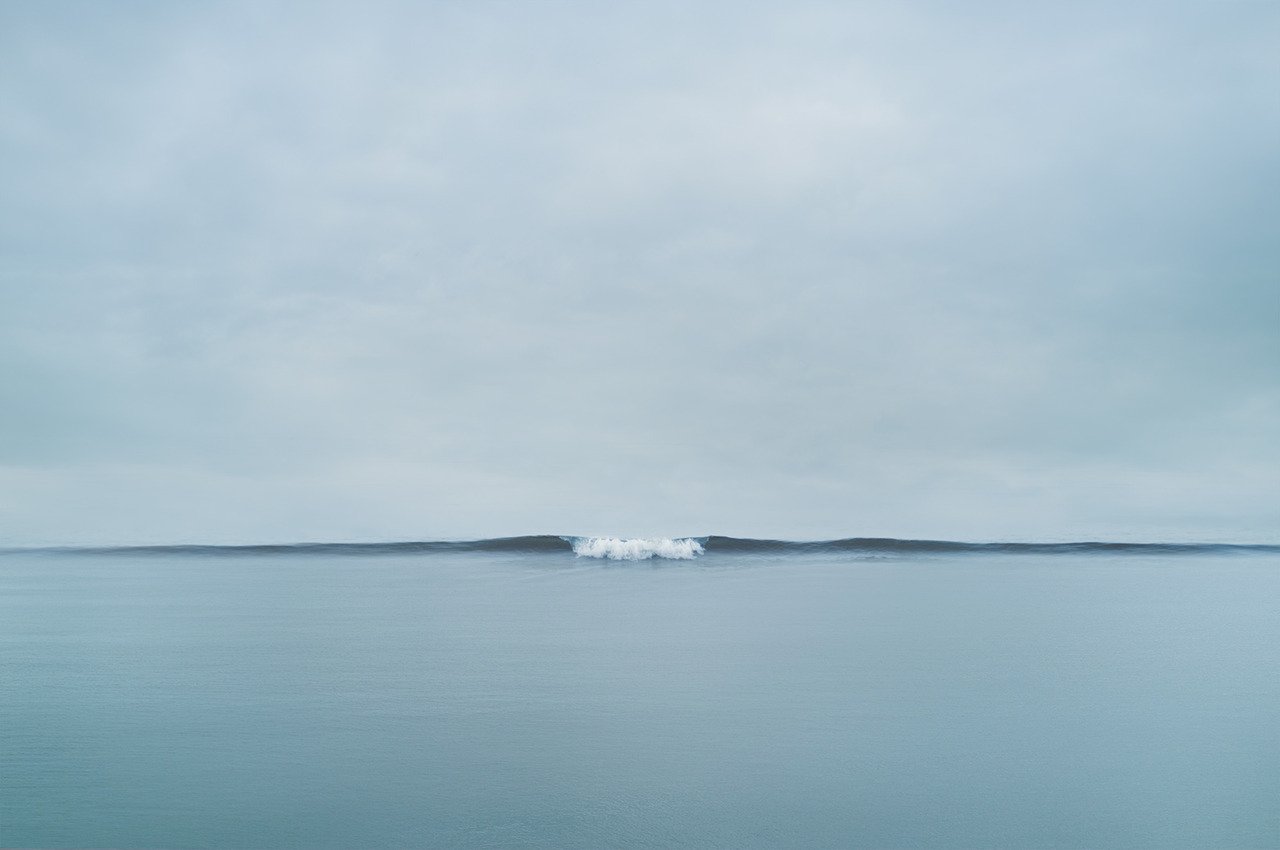 Small Ocean Wave Breaking With White Water Blue Horizon