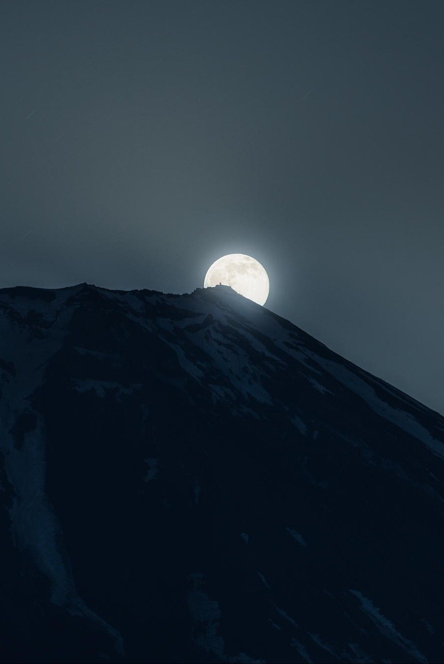 Full Moon Rising Behind Dark Mountain Peak Silhouette
