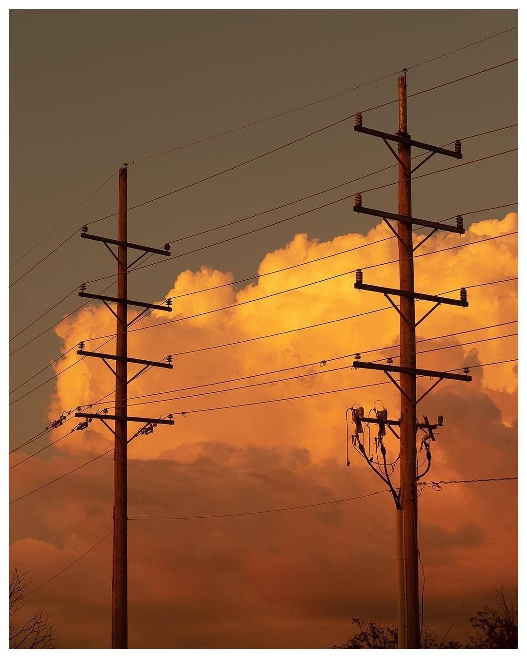 Wooden Power Line Poles Against Orange Sunset Clouds Sky