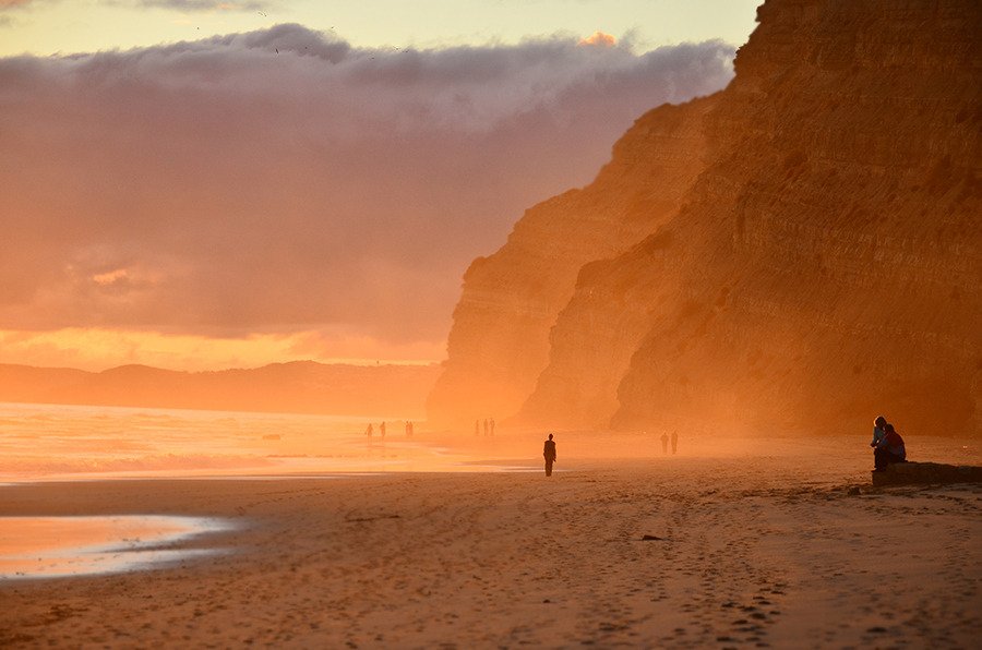 Person Walking Sandy Beach Orange Sunset Cliff Coast
